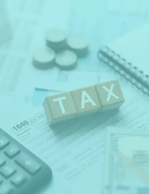 Sales tax filing services represented by wooden blocks that spell "tax", along with a calculator and notebook